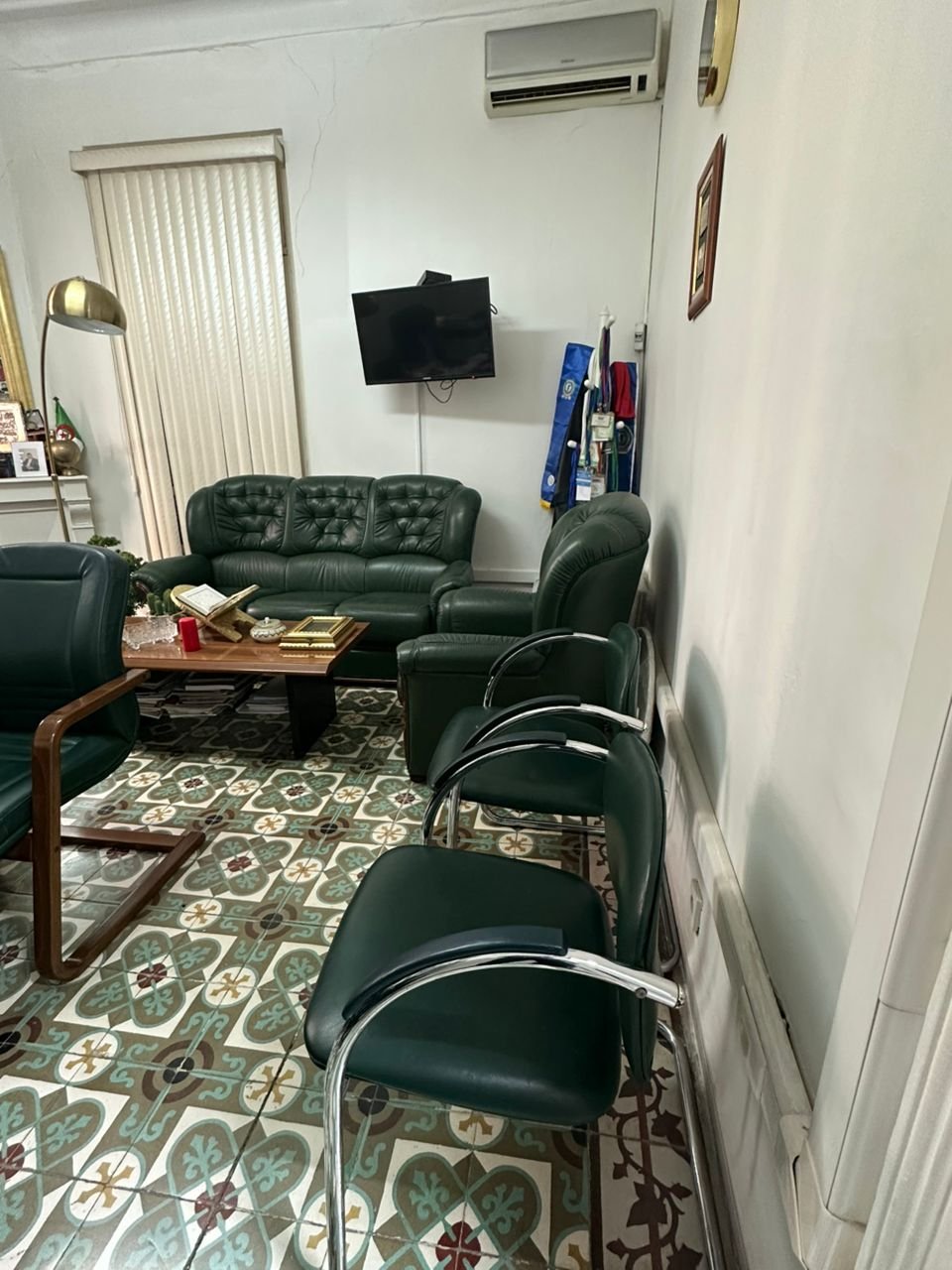 Bureau privé de la notaire avec canapés en cuir vert et carreaux de ciment